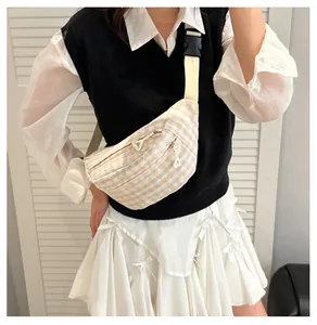 Detail of checkered crossbody bag showing dual zippers and adjustable fabric strap