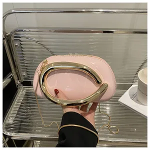 Détail du sac rond en cuir verni rose avec une poignée dorée en C et une bandoulière