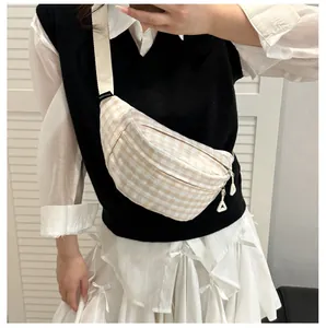 Detail view of plaid crossbody bag featuring adjustable nylon strap and metal zipper