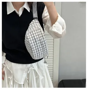 Close-up of grey and white checkered chest bag with adjustable strap and brand tag