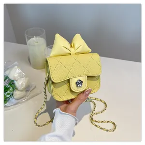 Macro shot of yellow quilted mini bag with flower clasp and leather chain strap detail