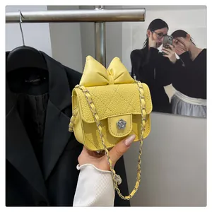 Detail of yellow quilted mini bag with oversized bow and camellia flower metal lock