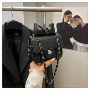 Detail of black quilted leather mini bag with bow decoration and silver floral buckle