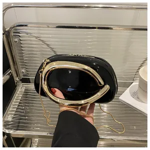 Détail du sac en cuir verni noir avec grande poignée anneau dorée et sa chaîne
