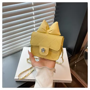Close-up of a yellow quilted mini bag with a large bow and silver camellia clasp