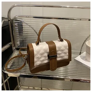 Détail du sac à main matelassé marron et blanc avec fermoir en métal doré sur étagère