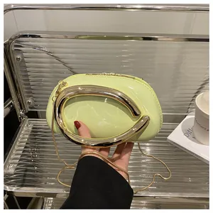Détail d'un sac en cuir verni vert clair avec une poignée métallique dorée en C