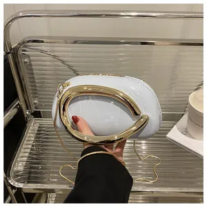 Détail d'un sac rond bleu clair avec poignée dorée en demi-cercle et bandoulière