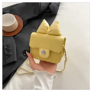 Detail of yellow quilted bag with oversized bow and silver camellia metal clasp