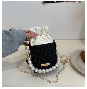 Detail der karierten Beuteltasche mit großem Perlengriff und goldener Kette auf Tisch