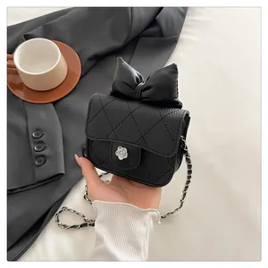 Detailed macro view of black quilted mini bag featuring silver camellia lock and bow