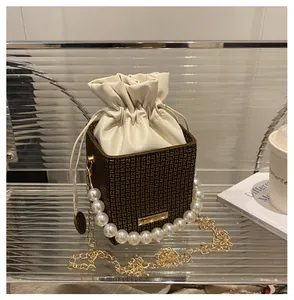 Detailansicht der karierten Beuteltasche mit goldener Kette und elegantem Perlengriff