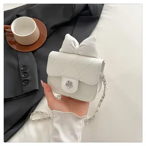 Detail of white quilted crossbody bag featuring large bow and camellia metal lock