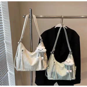 Détail de deux sacs hobo en crème et vert menthe sur cintres avec des breloques peluche