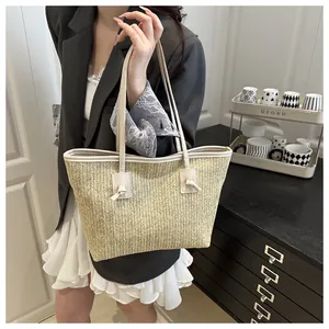 Detail view of woven straw tote bag with cream leather straps and elegant knotted loop design