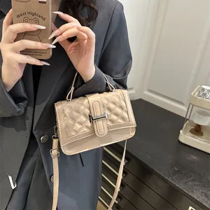 Sac bandoulière beige à motif matelassé avec boucle en H argentée porté par un mannequin