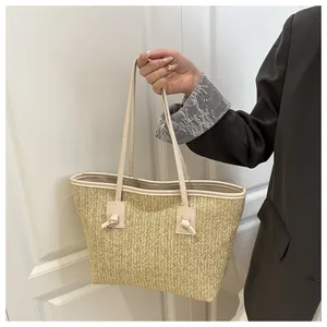 Close-up of woven straw tote bag featuring detailed knotted handles and beige texture