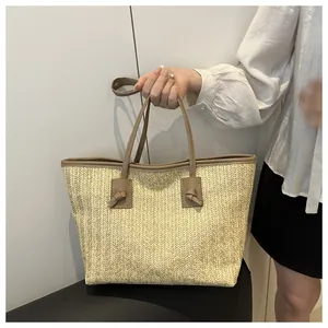Close-up of straw woven tote with brown leather handles and decorative knots
