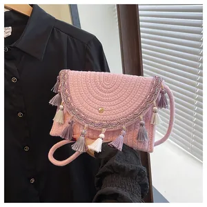 Close-up of pink woven crossbody bag with colorful tassels and ethnic embroidery details