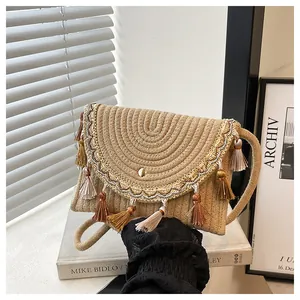 Detail of woven straw envelope bag with ethnic tassels and gold embroidery trim