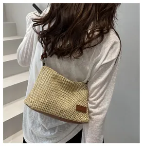 Détail du sac bandoulière en paille avec bordure en cuir marron et anneau métallique