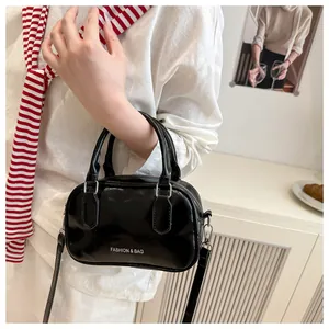 Détail d'un mini sac à main noir brillant minimaliste avec lettrage et bandoulière