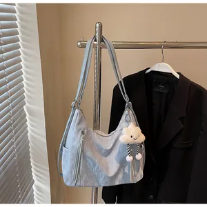 Détail du sac bandoulière bleu clair avec texture marbrée, zips et pendentif en peluche