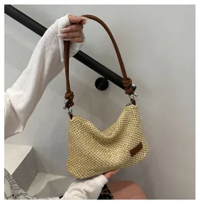 Détail du sac à main en paille tressée avec bandoulière en cuir marron et nœud