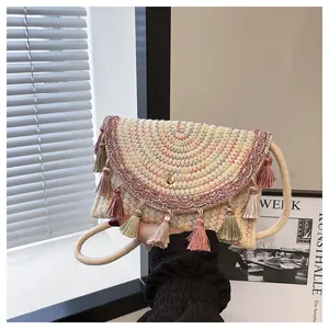 Detail of woven straw envelope bag featuring colorful stitching and vibrant layered tassels