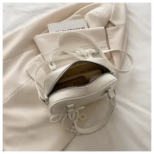 Détail de l'intérieur du sac crème avec pochette marron et breloque en perles