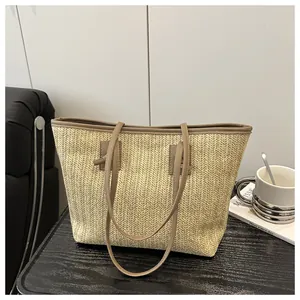 Detailed macro view of herringbone straw weave texture and brown leather strap on tote bag