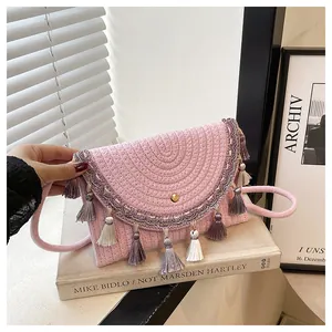 Macro detail of pink woven envelope bag featuring gradient tassels and gold metal clasp