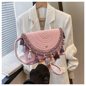Close-up of pink woven handbag with bohemian tassels and decorative patterned trim