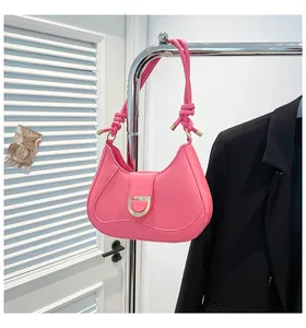 Detail of bright pink crescent bag featuring a gold D-buckle and decorative knotted strap