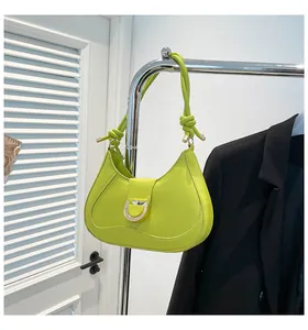 Close-up of neon green crescent shoulder bag with golden D-ring buckle and knotted strap