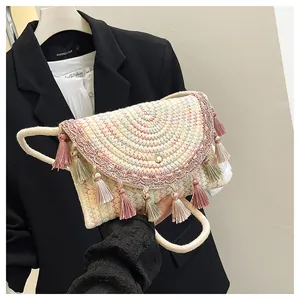Detail of bohemian straw woven crossbody bag with colorful tassels and a gold buckle