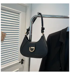 Detail view of black crescent bag featuring golden D-buckle and elegant knotted strap