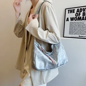 Silver metallic hobo bag with pink ribbon scarf detail worn on a beige blazer