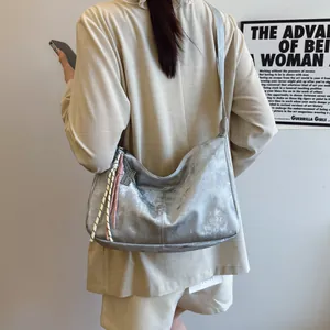 Detail of silver metallic tote bag with pink rope charm and woven tassel accent