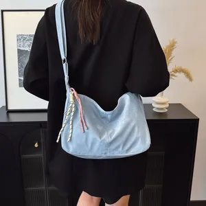 Detail of light blue crossbody bag with braided rope charms and lychee leather texture