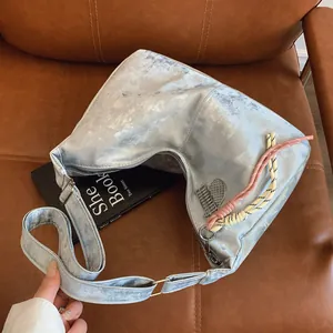 Detail of silver-grey hobo bag with tennis racket charm and woven cord on a leather seat