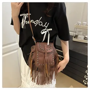 Bolso bandolera bohemio marrón con flecos y tachuelas plateadas usado por modelo