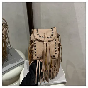 Primer plano del bolso beige con flecos de cuero y remaches metálicos estilo bohemio