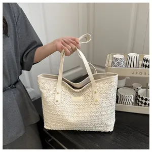 Detail of hollow out crochet pattern and rivet reinforcement on beige straw tote bag