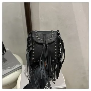 Detalle de bolso bandolera de piel negra con flecos de estilo punk y remaches plateados