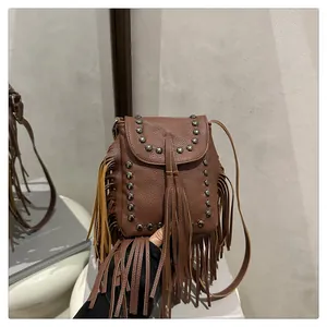 Detalle de bolso bandolera marrón con flecos, remaches vintage y textura de cuero granulado