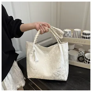 Detail of lace tote bag featuring floral butterfly jacquard and braided rope handles