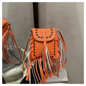 Detalle de bolso bandolera de cuero naranja con flecos y remaches metálicos de estilo bohemio