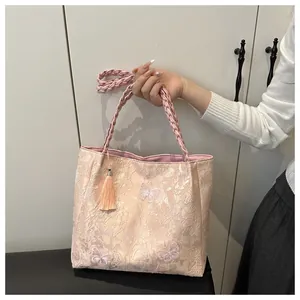Detail showing the lace embroidery texture with butterfly patches and tassel on the pink bag