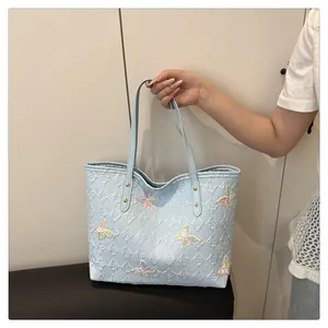 Detail of light blue tote bag with embossed textures and colorful glitter butterfly accents
